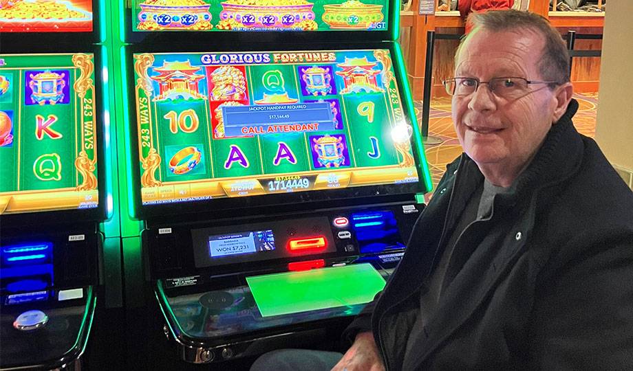 Jackpot winner Butch smiling in front of his winning video gaming machine