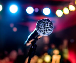 Microphone on a stage with crowd and lights in the background.