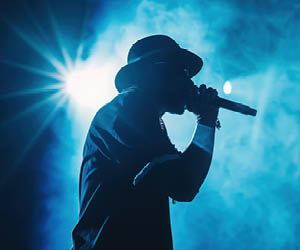 Person singing into a microphone with blue stage light.